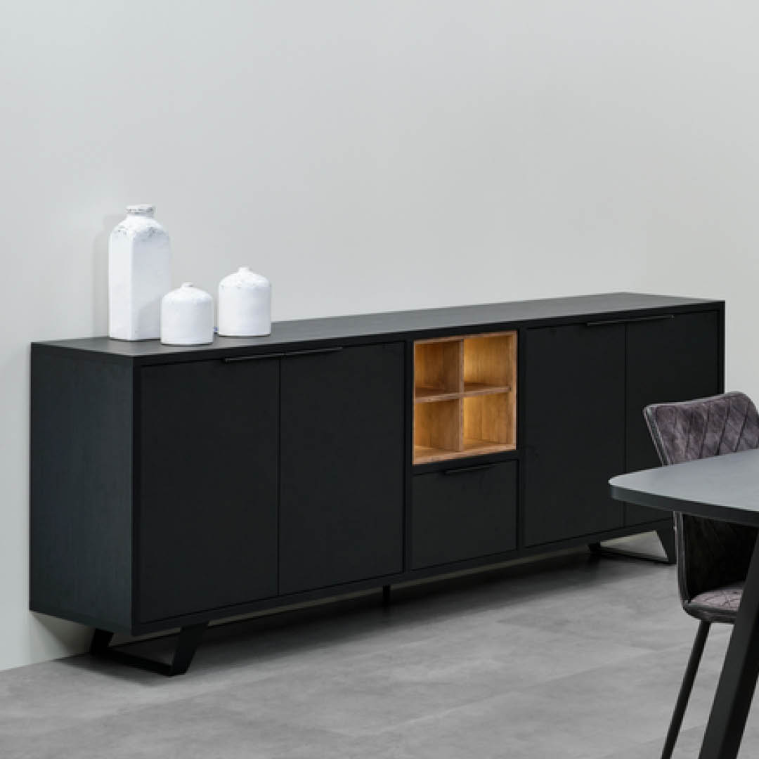 Buffet noir avec quatre portes, quatre niches ouvertes avec des accents en bois chaleureux et un éclairage intégré, ainsi qu’un tiroir. Le meuble repose sur des pieds métalliques inclinés pour une allure moderne.