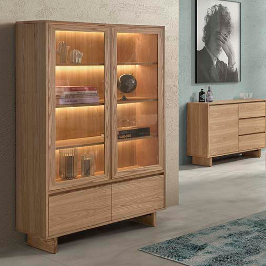 Klassieke vitrinekast in massief hout met 2 glazen deuren, 3 houten legplanken en 2 lades onderaan. Warme LED-verlichting benadrukt de inhoud.