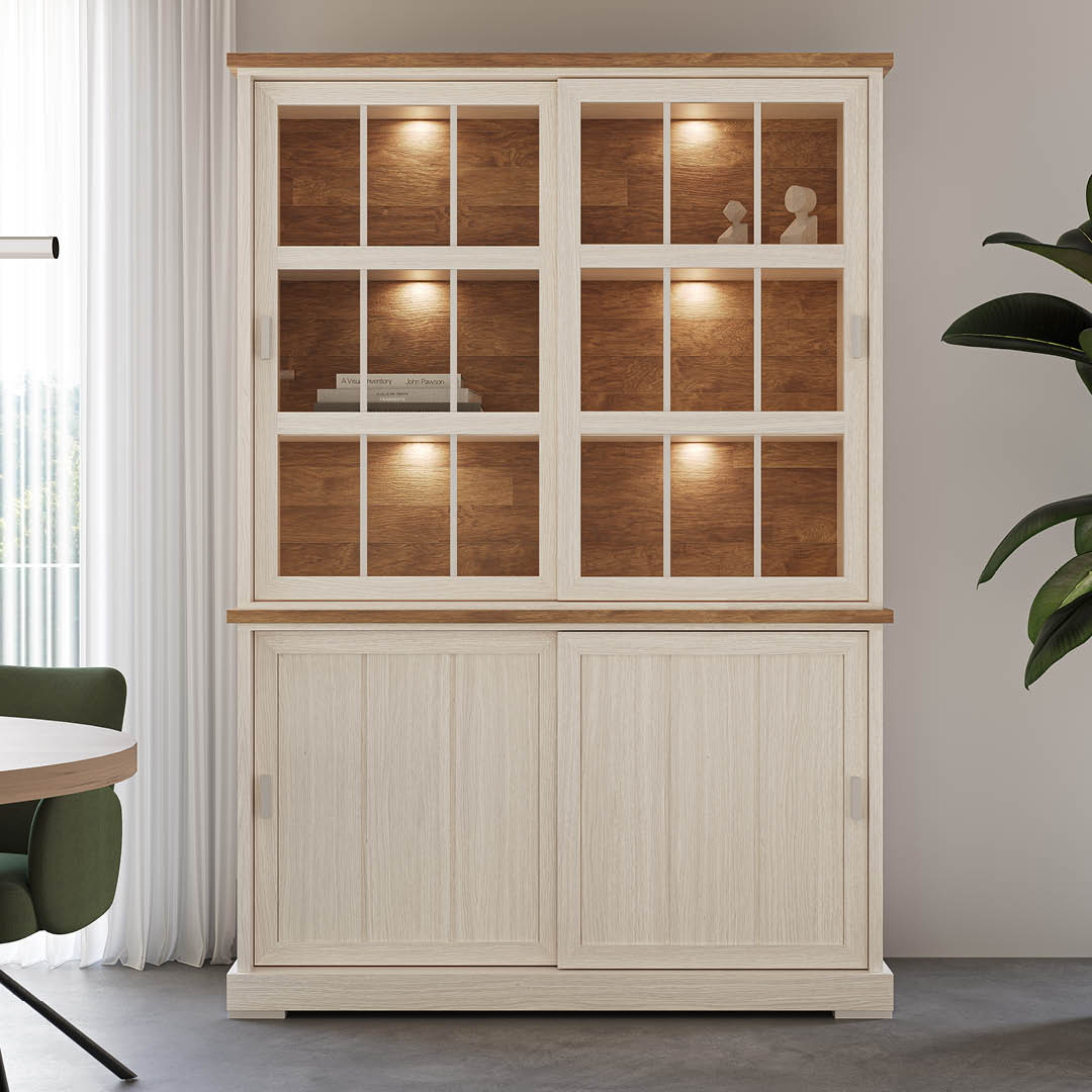 Elegante vitrinekast in wit met een houten blad. Beschikt over 2 schuifdeuren, 3 glazen legplanken en 2 gesloten opbergvakken onderaan.